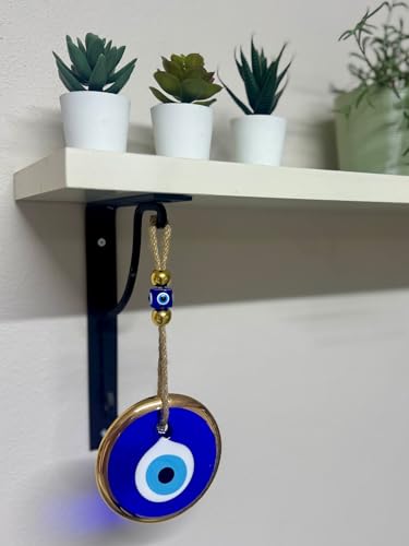 Blue evil eye pendant hanging from a shelf with plants in the background