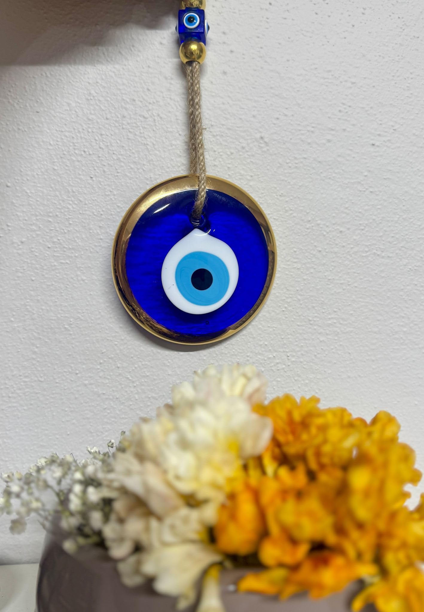Decorative evil eye pendant with floral arrangement on a light gray background
