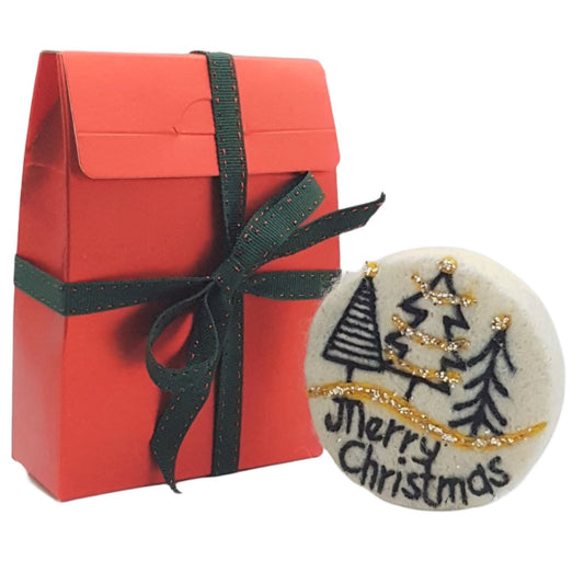 Red gift box with green ribbon and a round Christmas-themed item on a white background