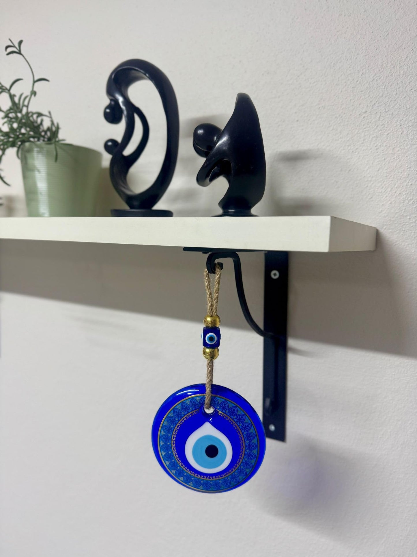 Blue evil eye pendant hanging from a shelf with decorative items.