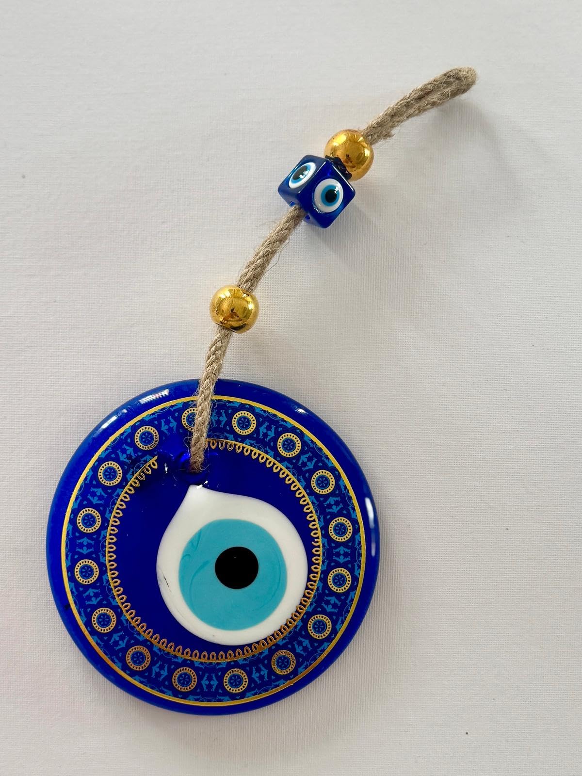 Blue evil eye charm with gold beads on a white background