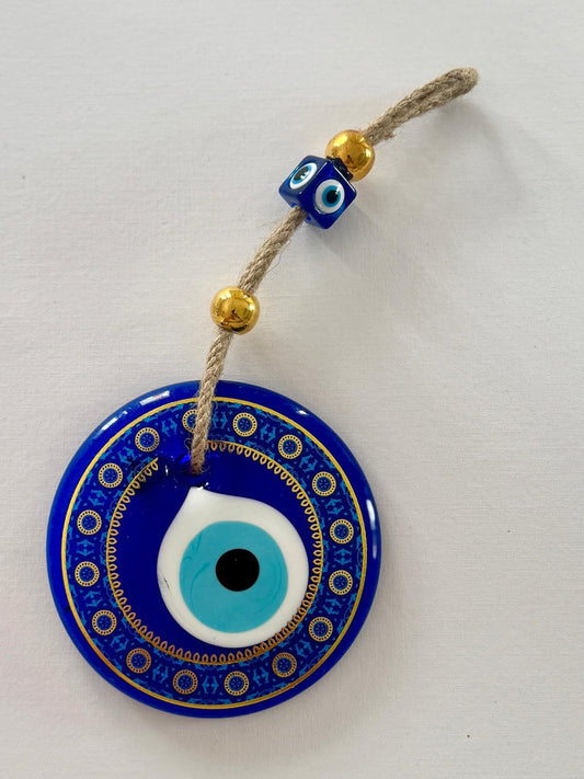 Blue evil eye charm with gold beads on a white background