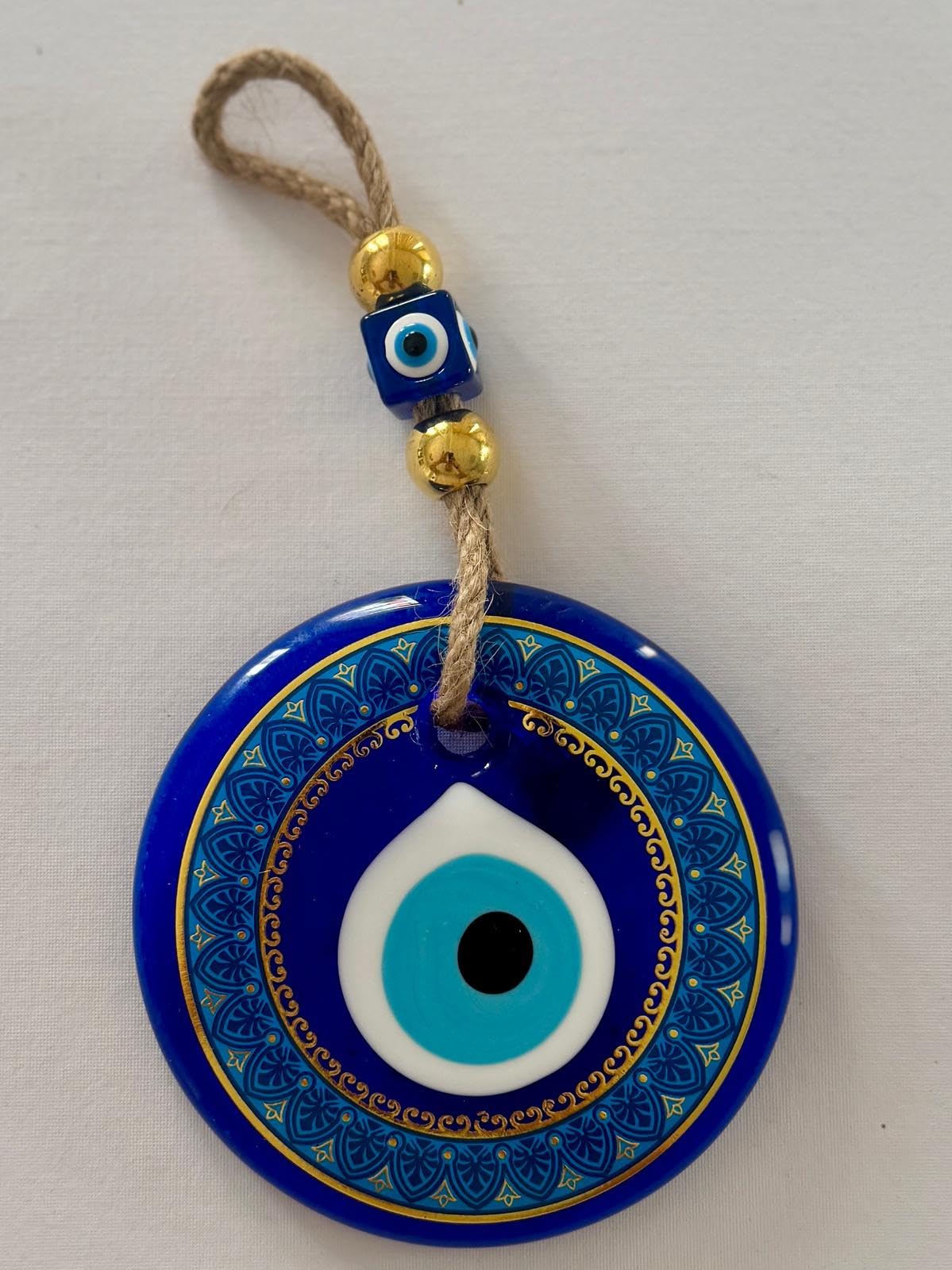 Blue evil eye charm with gold accents on a white background